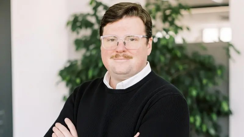 Corey standing in an office with arms crossed