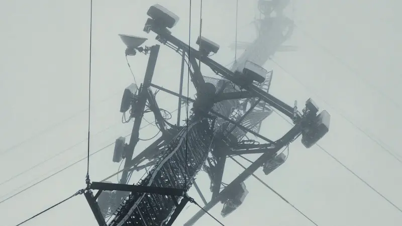 A cell phone tower extending up into the foggy clouds